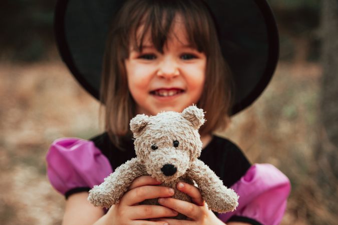 Smiling girl with teddy bear in halloween costume