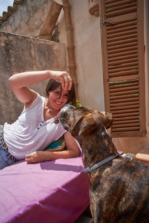Young woman lying on mattress and offering treat to pet