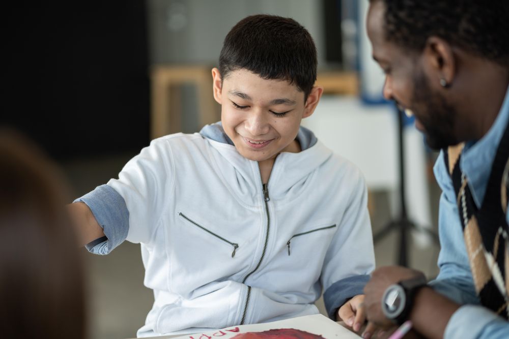 Boy smiling with his teacher in an arts class