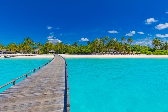 Walkway above blue water leading to beach