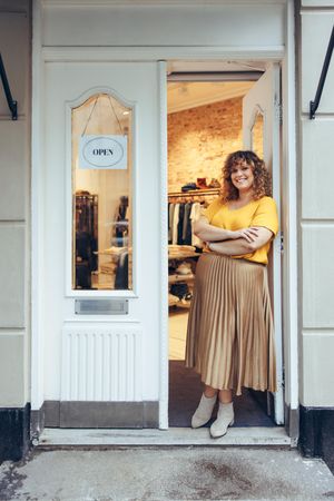 Businesswoman standing at entrance of her store looking at camera with her arms crossed