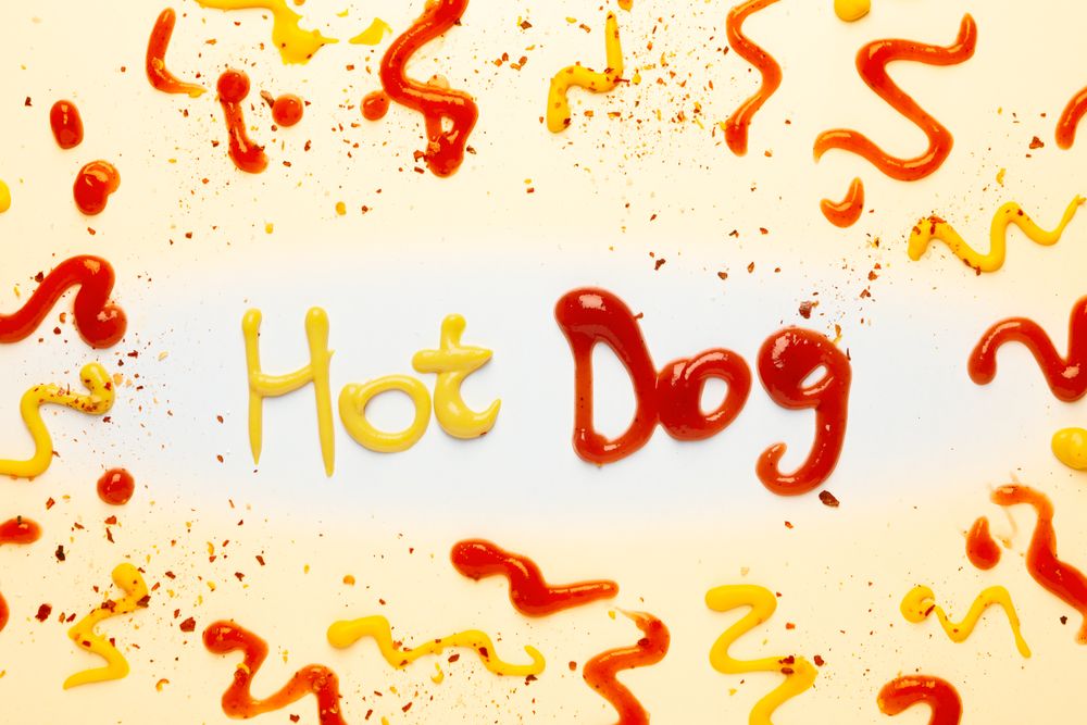 Inscription Hot dog made of sauces and spices on light background