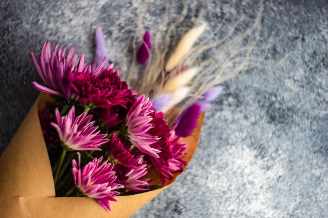 Aster flower bouquet wrapped in paper on stone background with copy space