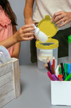 Girl recycling plastic with her teacher in an ecology classroom