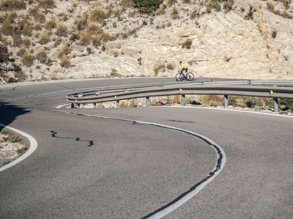 healthy man riding a bicycle on a mountain road in a sunny day