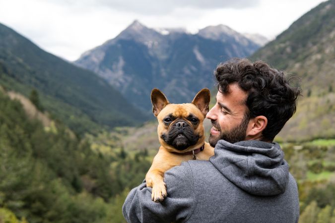 Happy traveling man embracing cute dog in highlands