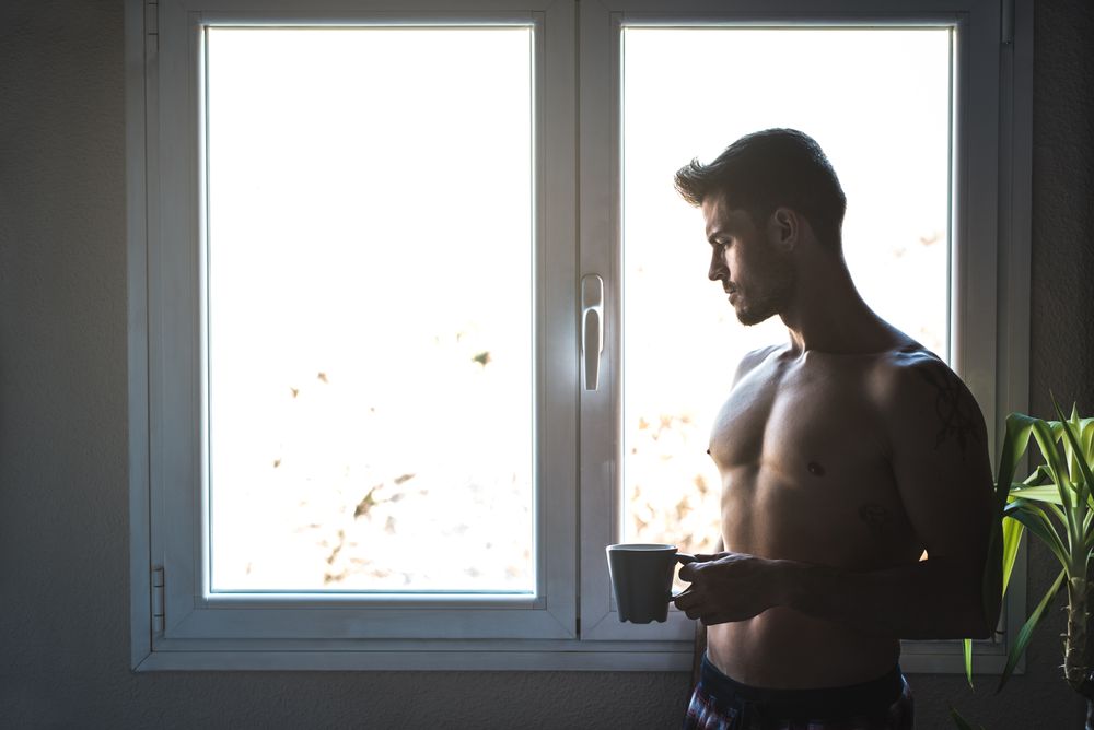 Man standing by a windows with a cup of coffee