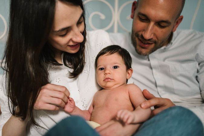 Parents hugging baby on bed