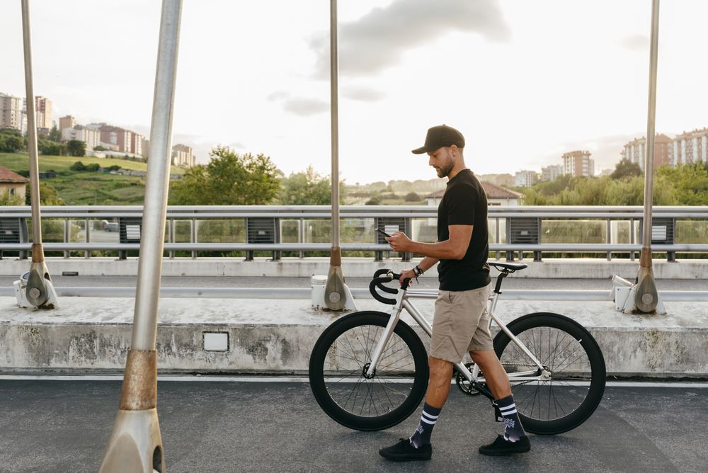 Man walking with bike and using smartphone