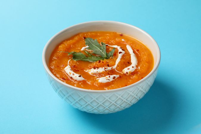 Bowl of pumpkin soup on blue table
