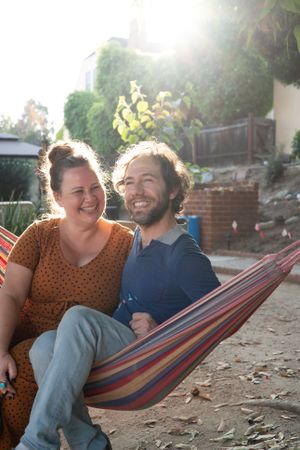 Woman smiling and looking at her boyfriend while both are sitting in hammock