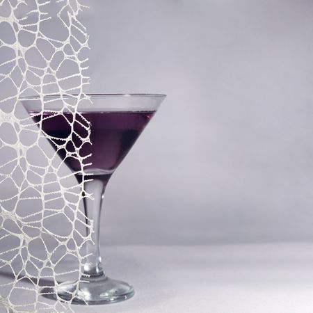 Dark cocktail in martini glass behind lace