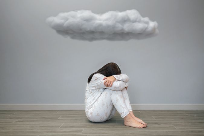 Woman with sad thoughts crying under a dark cloud