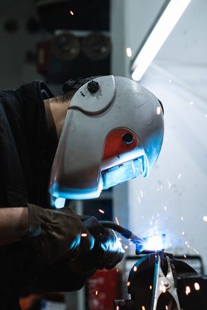 Anonymous mechanic welding metal construction in workshop