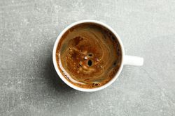 Cup of coffee on grey background, space for text
