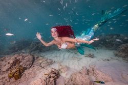 Redhead fairytale female mermaid swimming underwater