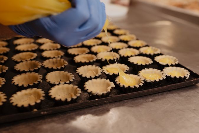 Crop baker squeezing dough on tray