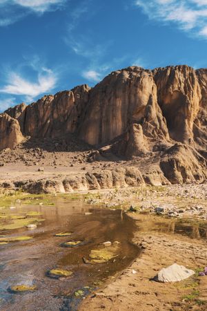 Narrow river near stone hill in desert