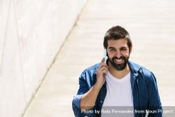 Smiling man in denim walking outside talking on phone 5aYeQ5