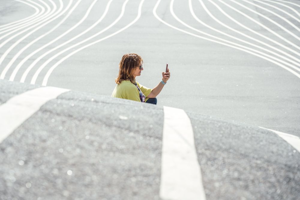 Modern relaxed woman on marked road and browsing smartphone