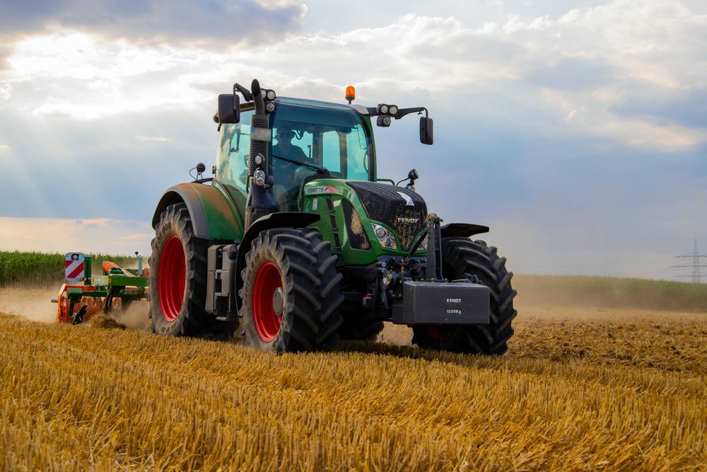 Man driving tractor on brown grass field