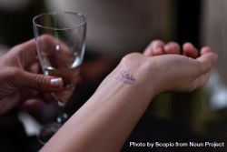 Person holding alcoholic drink and looking at their stamped wrist 5QkYeb