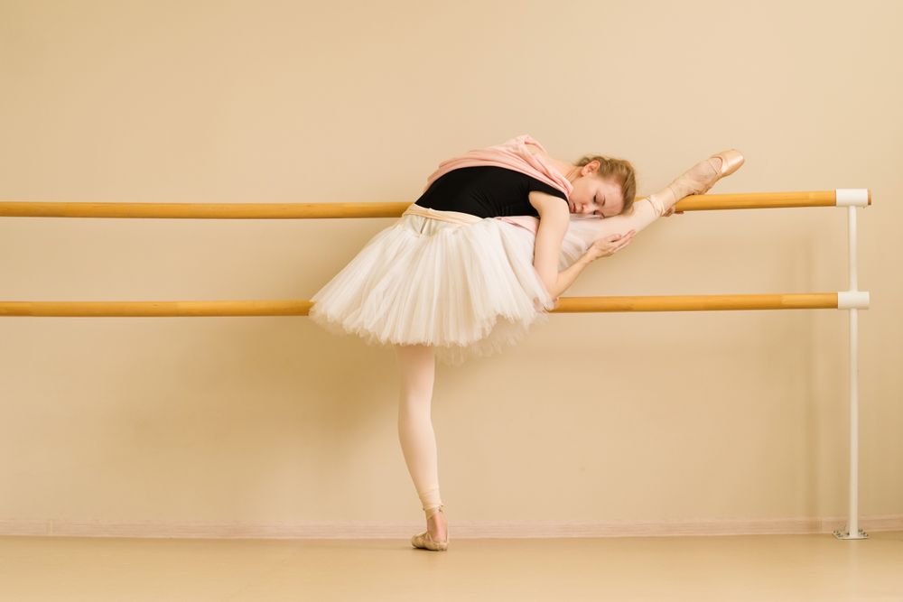 Ballerina stretches with her leg on barre