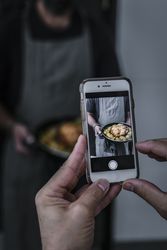 Person photographing cook and dish