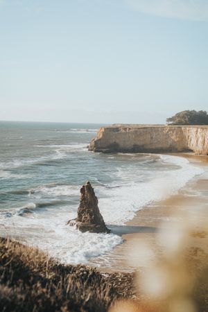 Aerial photography of huge rock on sandy shore