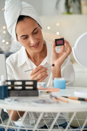 Woman applying eyeshadow on hand with brush