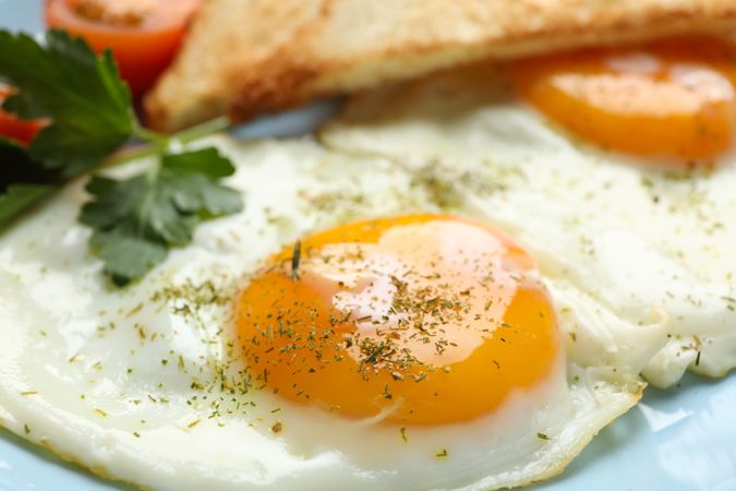 Close up of blue plate with two sunny side up eggs and toast