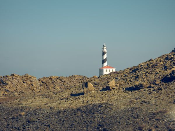 Lighthouse tower with house behind rough rocky formations