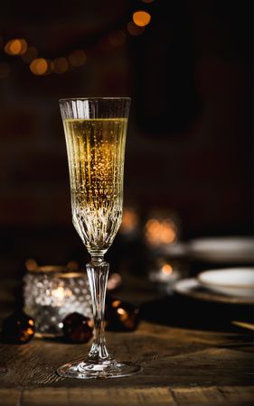 Crystal flutes full of champagne on wooden table, copy space