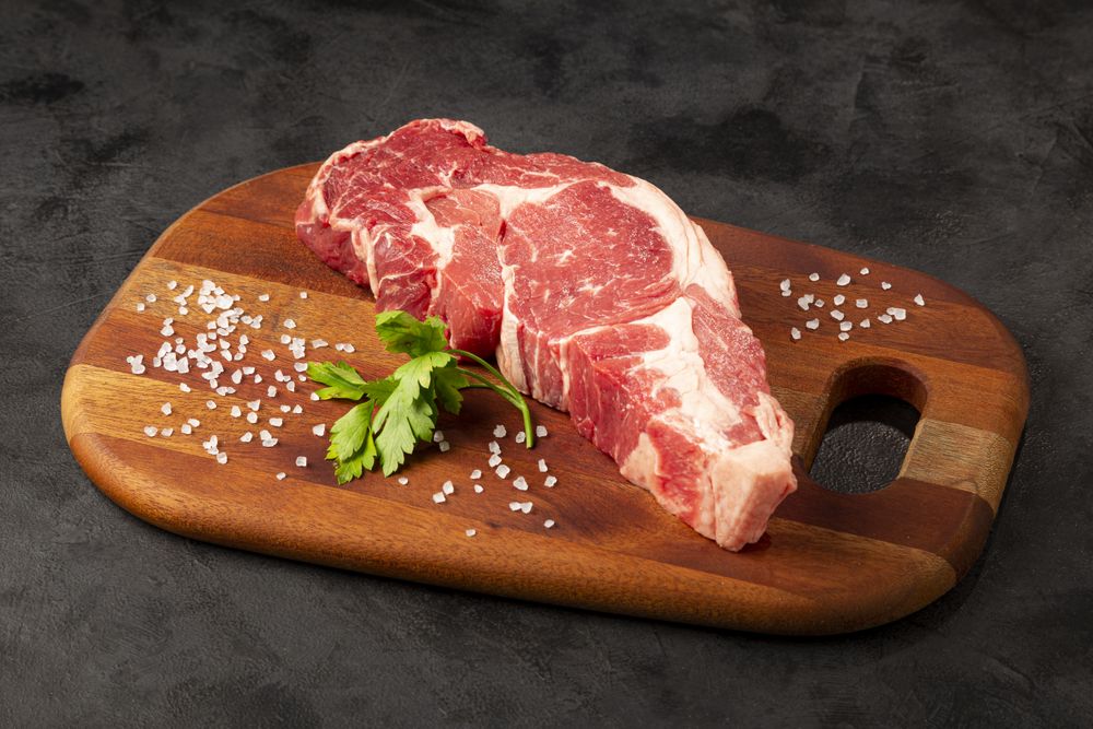 Raw ancho meat ready to roast on a wooden cutting board.
