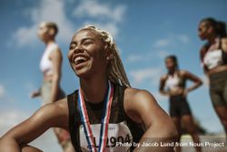 Female athlete smiling after winning a race with other competitors in background 41JmDb