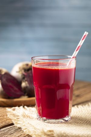 Red beet juice in a glass cup on the wooden table.