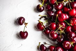 Top view of scattered sweet cherries on grey kitchen counter with space for text