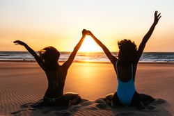 Content Black woman on tropical beach at sunset