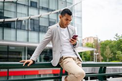 Man using smartphone leaning against wall