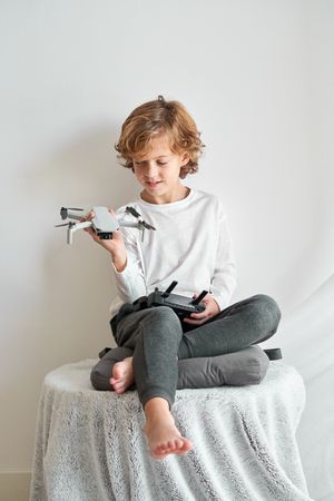 Content child sitting on table and looking at toy drone