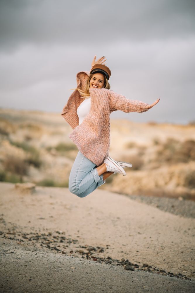 Cheerful woman jumping in desert landscape