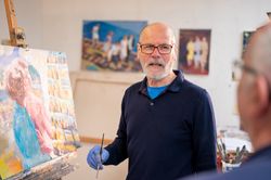 Male artist painting and talking to man