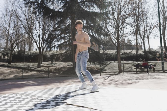 Shirtless man dancing break dance in park