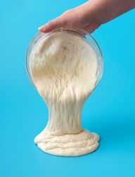 Pouring sourdough discard from a bowl directly on the blue table