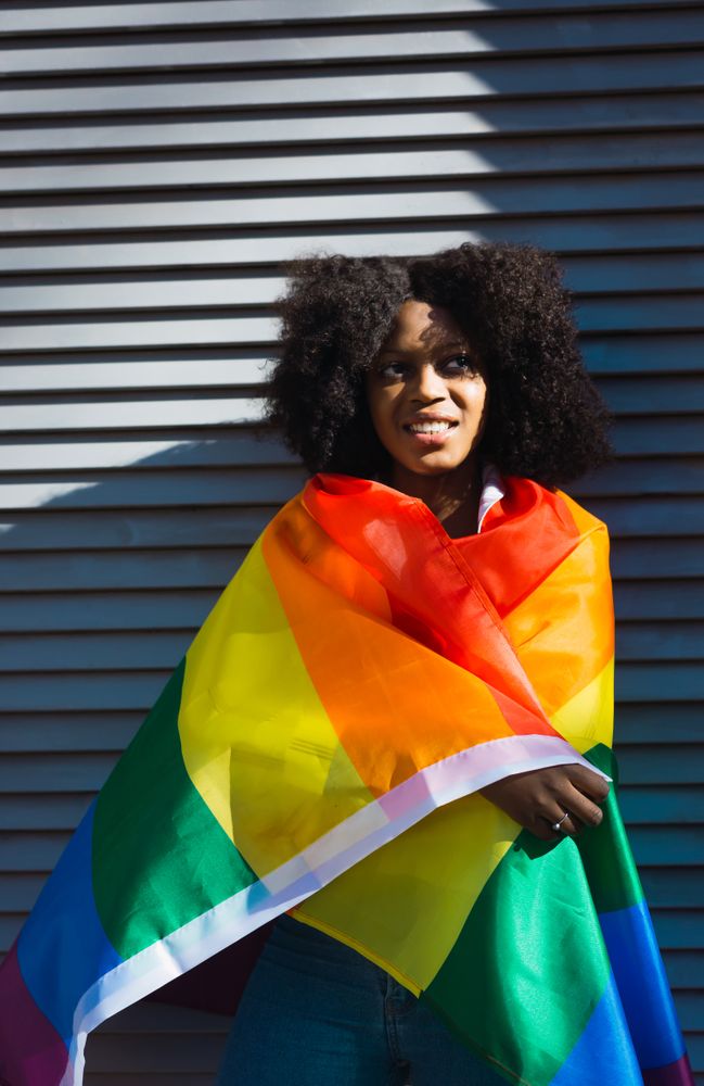 Black female posing happily with the LGBT flag