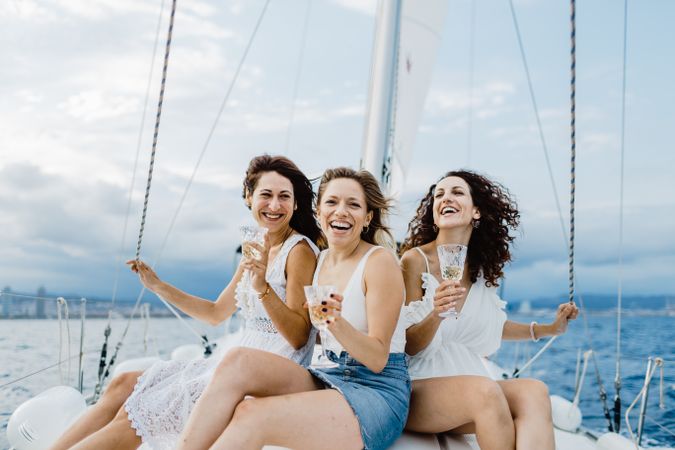 Cheerful friend with wine having fun on yacht