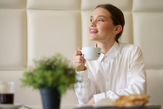 Happy businesswoman enjoying morning coffee in a chic cafeteria