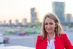 Happy woman in red standing with view of city behind her