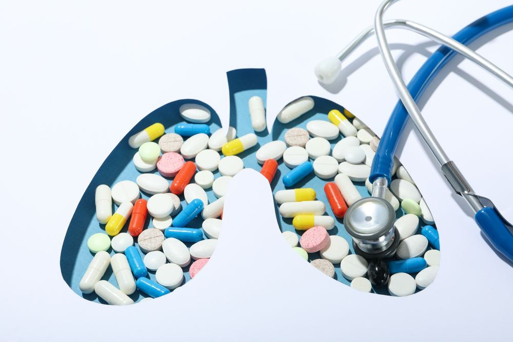 Close up of lung shape cut out of paper with pills underneath with doctor’s stethoscope