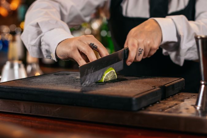 Close-up of a bartender cutting limes to prepare cocktails